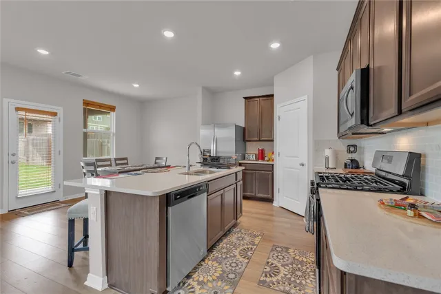 a kitchen with a stove a sink a microwave a dining table and chairs