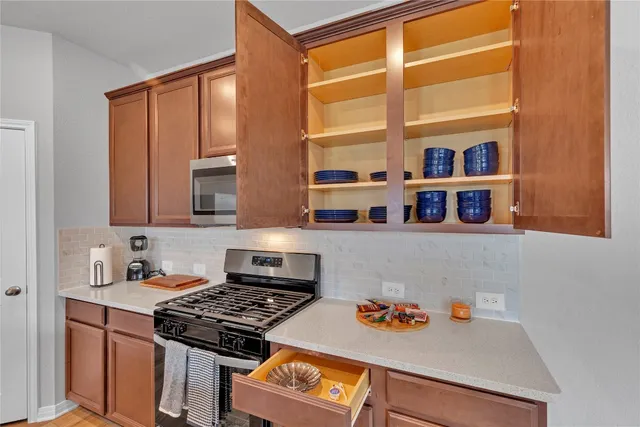 a kitchen with stainless steel appliances granite countertop a stove a sink and a microwave