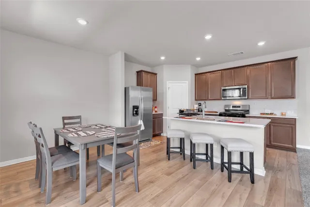 a kitchen with stainless steel appliances granite countertop a stove a refrigerator a kitchen island with a dining table and chairs