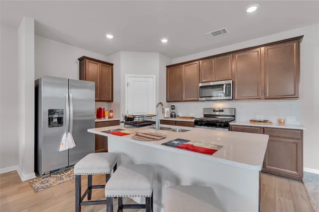 a kitchen with a sink a stove a refrigerator cabinets and a dining table