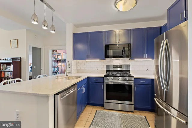 a kitchen with stainless steel appliances granite countertop a stove a sink dishwasher a microwave oven and a dining table with wooden floor