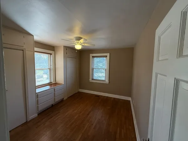 a view of an empty room with wooden floor and a window