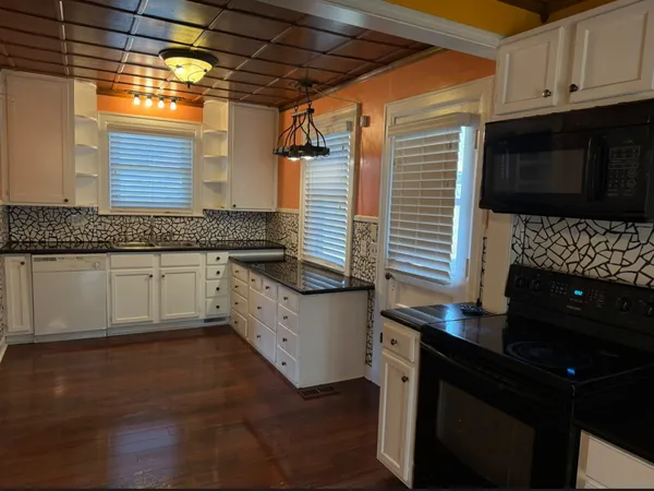 a kitchen with granite countertop white cabinets and black appliances