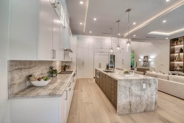 a kitchen with stainless steel appliances a table chairs sink and cabinets