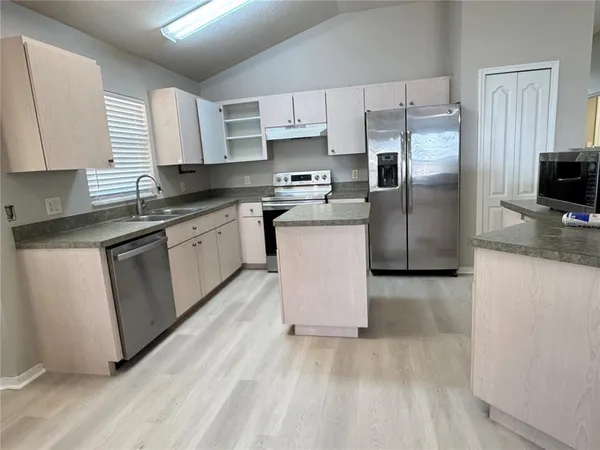 a kitchen with stainless steel appliances granite countertop a refrigerator sink and microwave