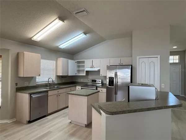 a kitchen with stainless steel appliances granite countertop a sink dishwasher stove top oven and refrigerator