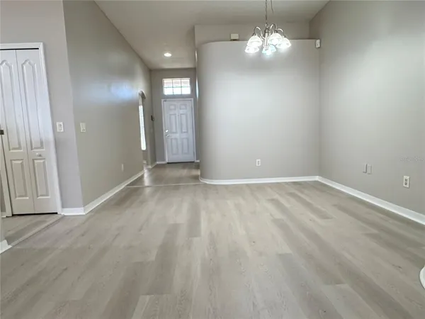 a view of an empty room with chandelier fan and refrigerator