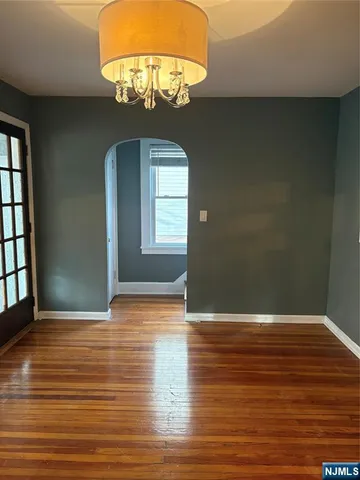 an empty room with wooden floor chandelier and windows