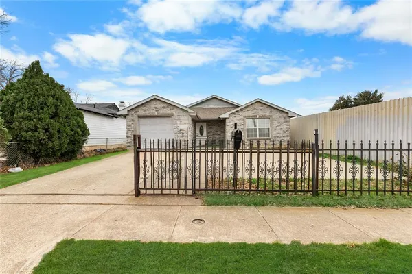 a view of a white house with a small yard and wooden fence