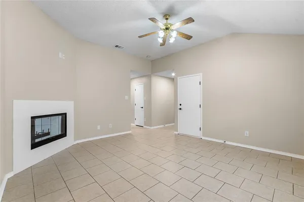 an empty room with a fireplace and a chandelier fan