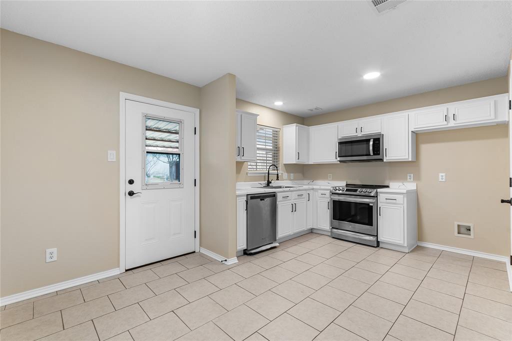 1035 North Ravinia Drive Dallas, TX 75211 - Photo 10 of 20 a kitchen with granite countertop white cabinets and stainless steel appliances