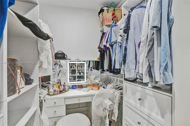 a view of walk in closet with clothes and shoes