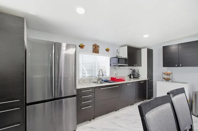 a kitchen with stainless steel appliances kitchen island sink refrigerator dining table and chairs