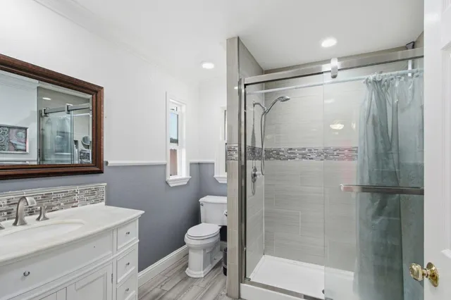 a bathroom with a shower sink vanity mirror and toilet