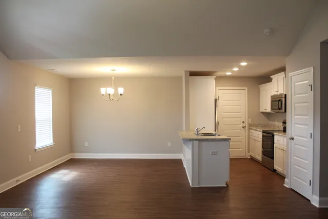 an empty room with kitchen view and wooden floor