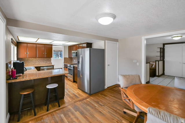 10 North Main Street Centerfield, UT 84622 - Photo 16 of 52 Kitchen with stainless steel appliances, brown cabinets, a kitchen breakfast bar, a peninsula, and a textured ceiling
