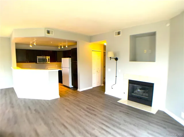 a view of a living room with wooden floor and a fireplace