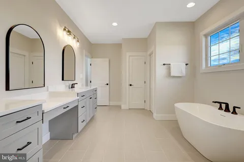 a large white bathroom with a double vanity sink a mirror and a bathtub