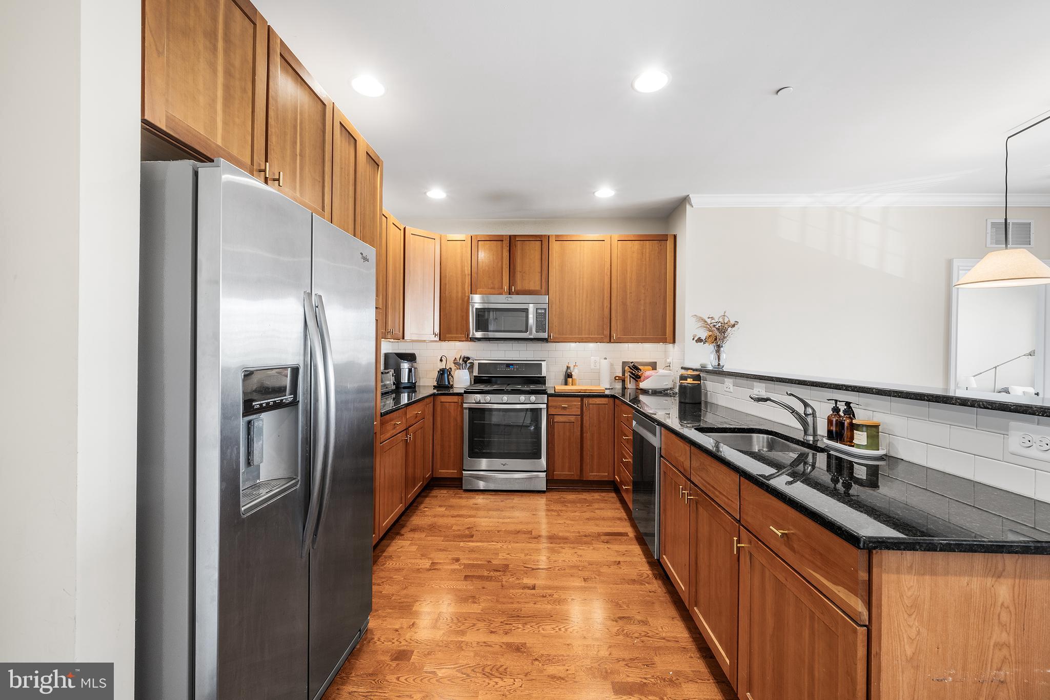 700 Commodore Court, Unit 2718 Philadelphia, PA 19146 - Photo 5 of 36 a kitchen with stainless steel appliances granite countertop a refrigerator a sink a stove top oven a kitchen island and couches