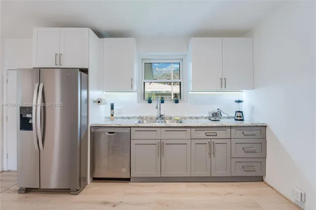 a kitchen with stainless steel appliances granite countertop a refrigerator and a sink