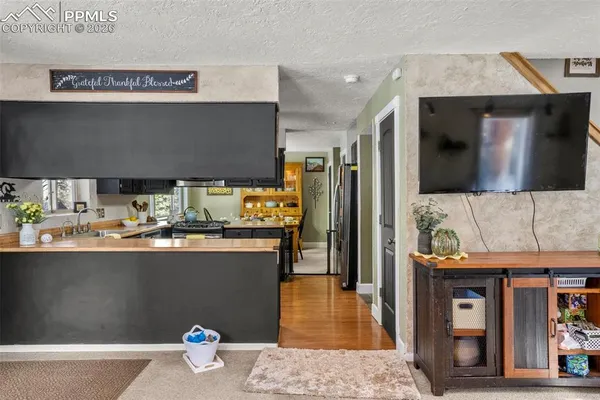 a kitchen with stainless steel appliances wooden floor and view living room