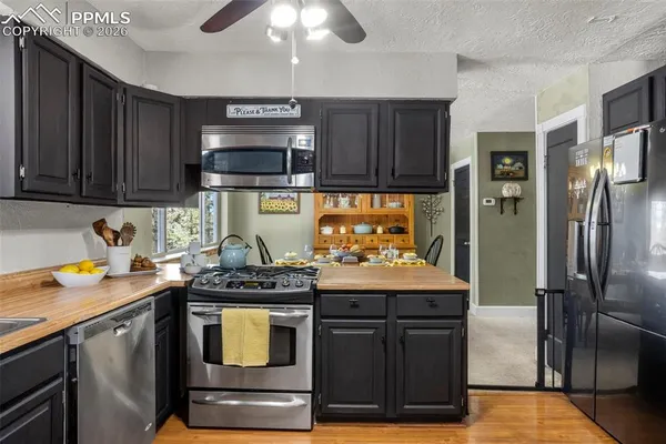 a kitchen with stainless steel appliances granite countertop a refrigerator a stove and a sink
