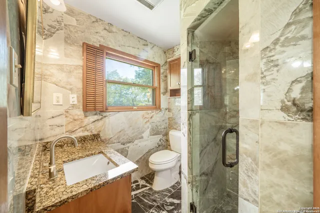 a bathroom with a granite countertop sink a toilet and shower