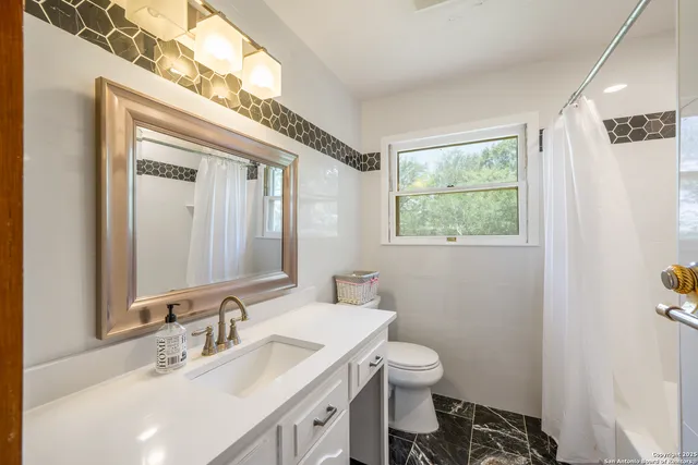 a bathroom with a granite countertop sink a toilet and a mirror