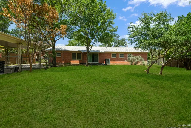 a view of a house with a big yard and large trees