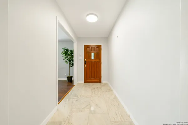 a view of a hallway with wooden floor and a bathroom