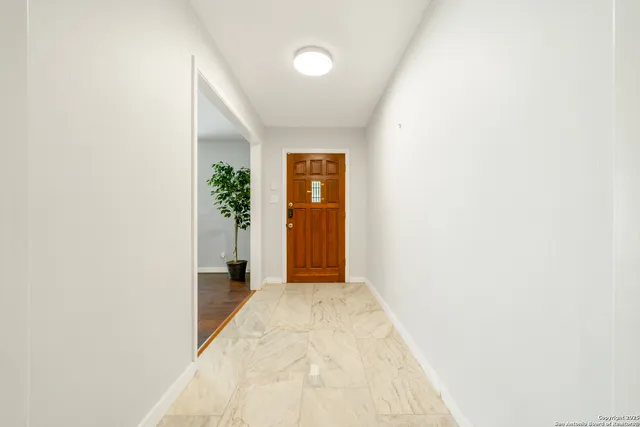 a view of a hallway with wooden floor and a bathroom