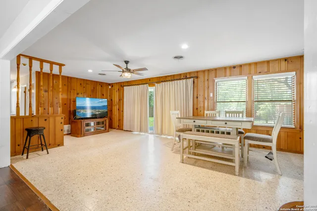 a living room with furniture a flat screen tv and large windows