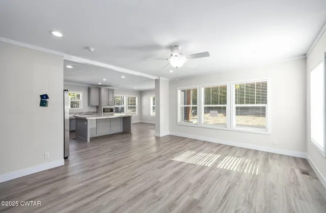 a view of an empty room with a window and wooden floor