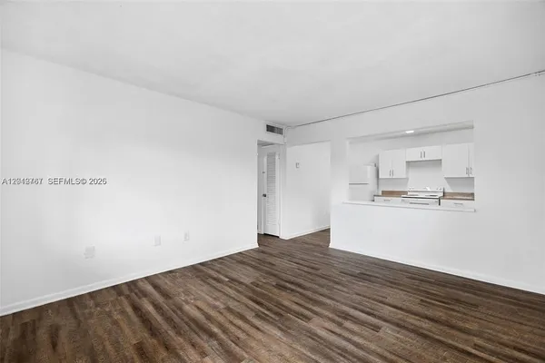 a view of kitchen and empty room with wooden floor