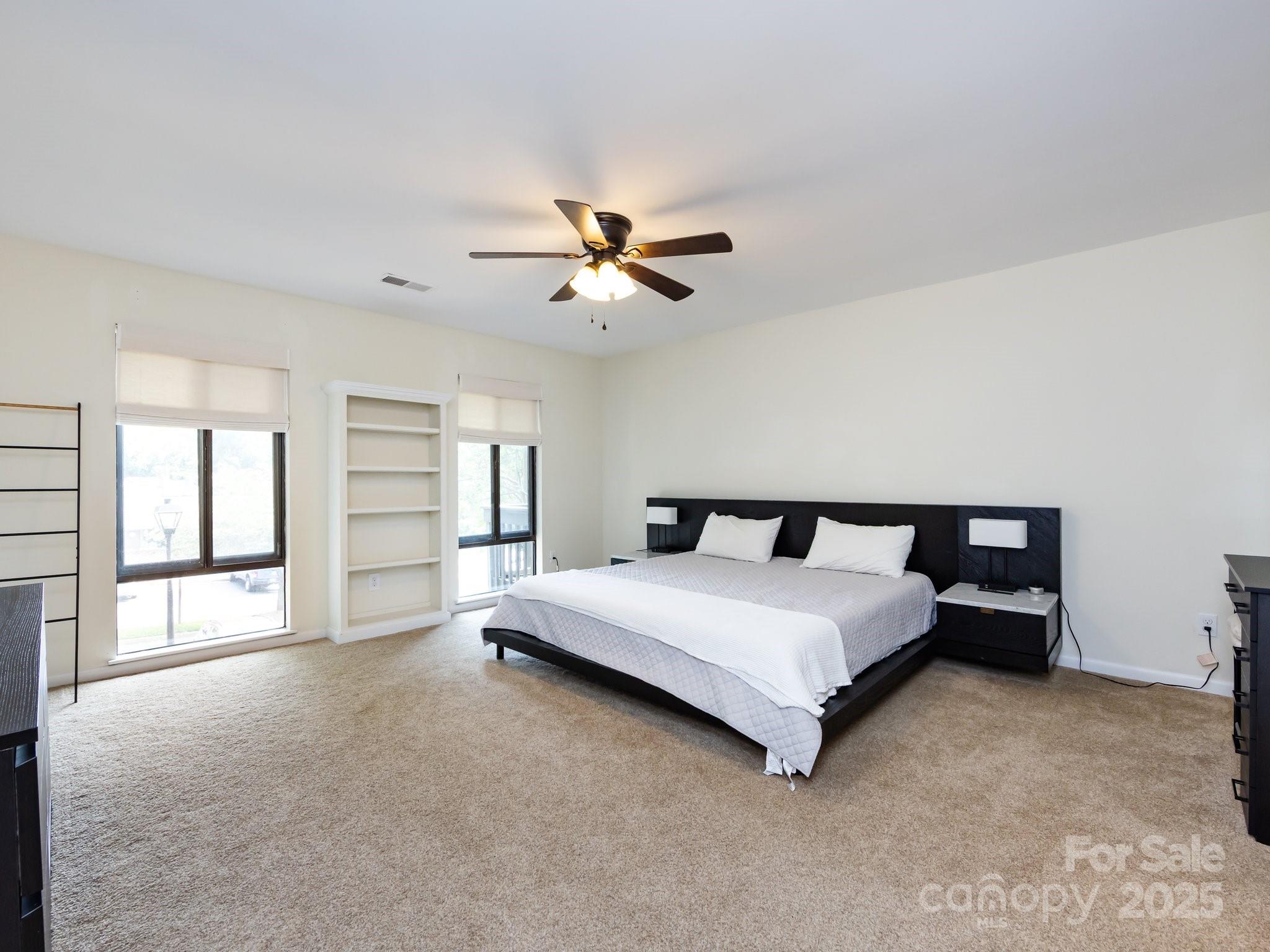 5809 Sharon Road, Unit G Charlotte, NC 28210 - Photo 12 of 25 a spacious bedroom with a bed and a ceiling fan in it