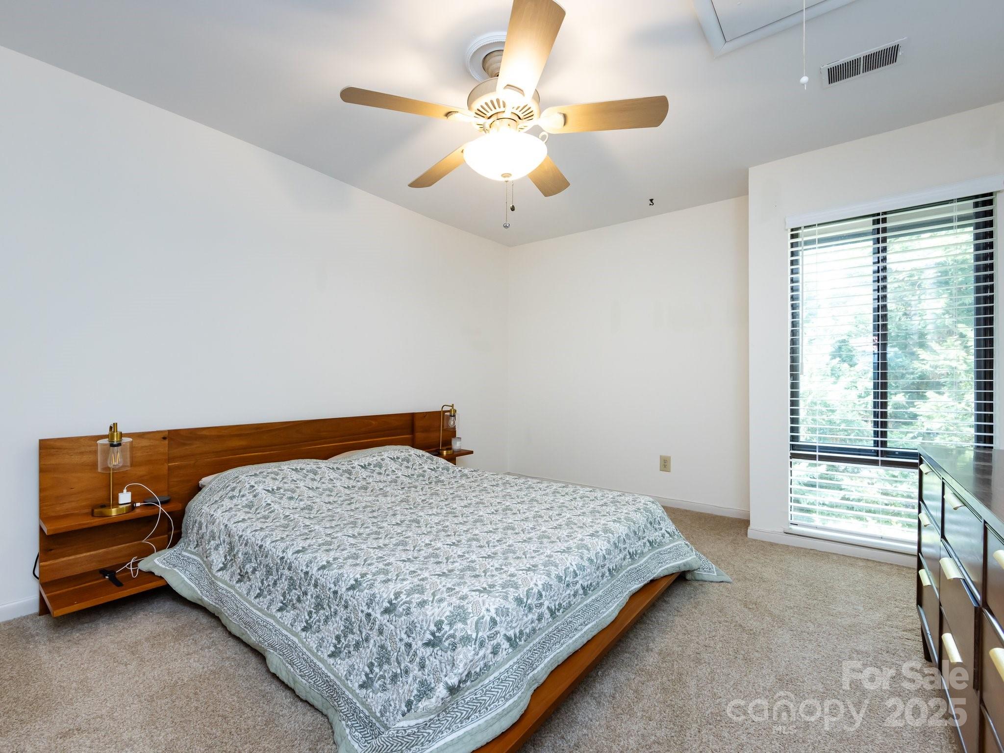 5809 Sharon Road, Unit G Charlotte, NC 28210 - Photo 16 of 25 a bedroom with a bed and a chandelier fan