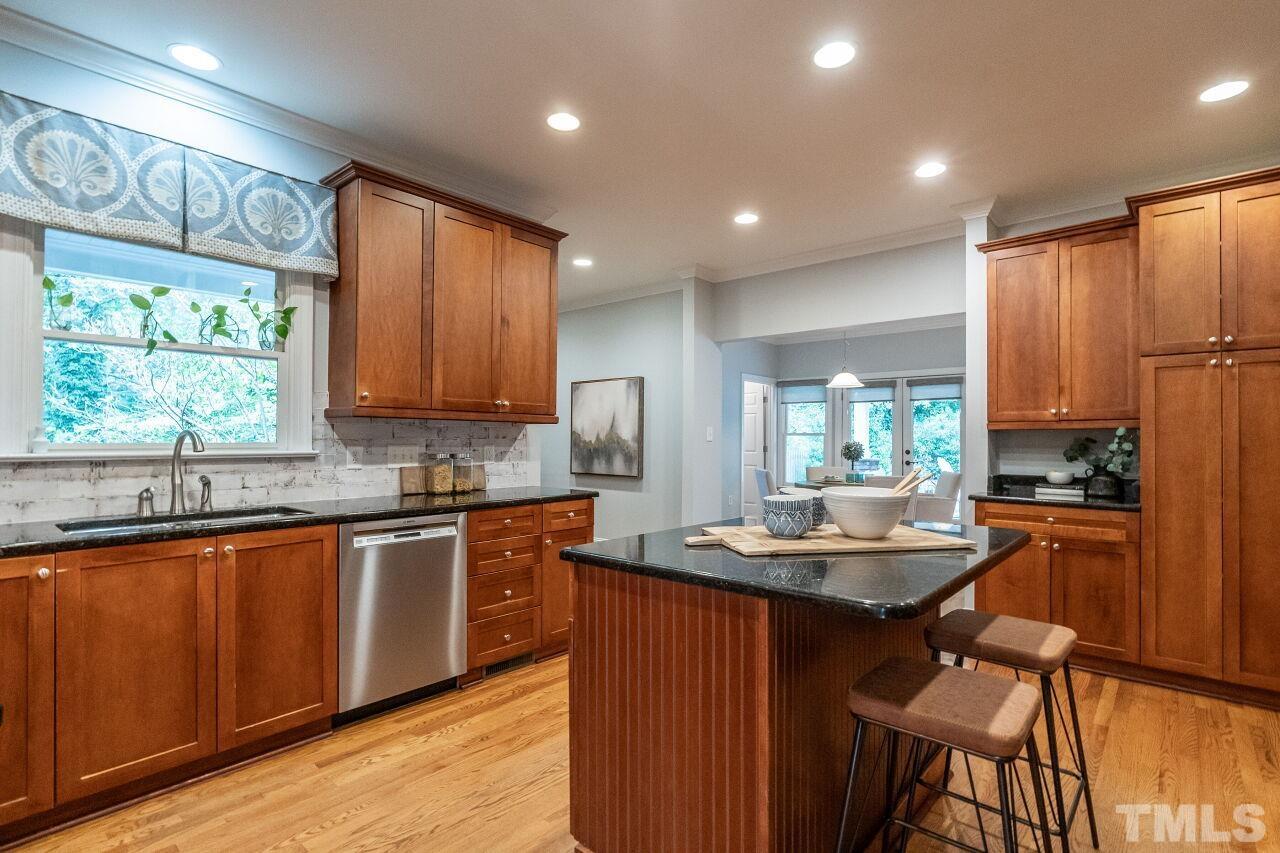 2730 Rothgeb Drive Raleigh, NC 27609 - Photo 19 of 43 a kitchen with kitchen island granite countertop wooden floors stove sink and cabinets
