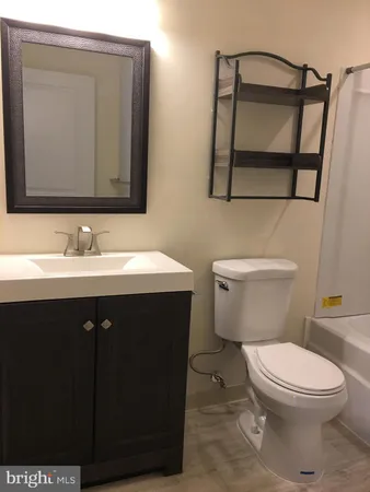a bathroom with a granite countertop toilet sink and mirror