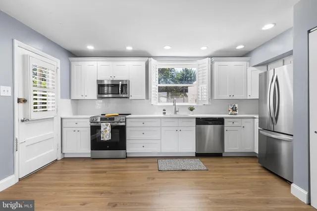 a kitchen with a sink cabinets stainless steel appliances and a window