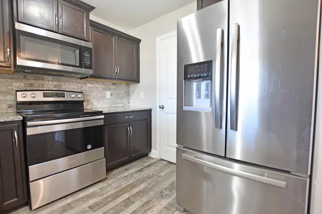 a kitchen with stainless steel appliances granite countertop a refrigerator microwave and sink