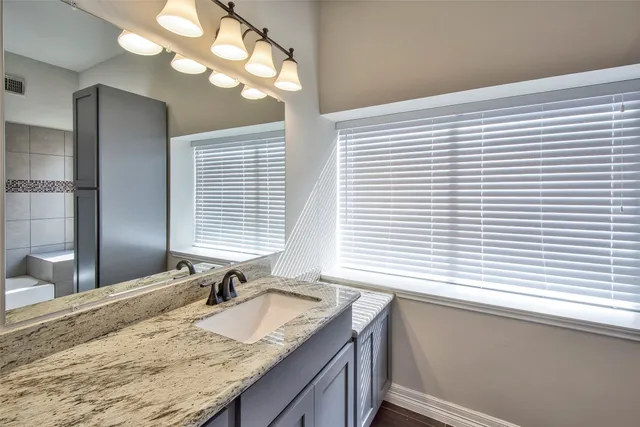 a bathroom with a granite countertop sink and a large mirror