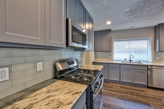 a kitchen with stainless steel appliances granite countertop a stove a sink and a microwave