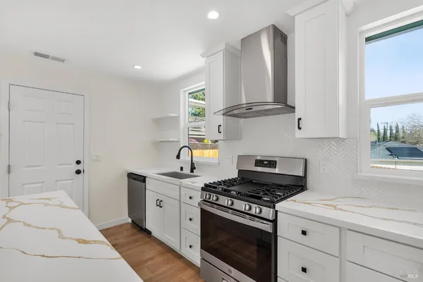 a kitchen with stainless steel appliances granite countertop a stove a sink and a refrigerator