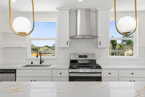 a kitchen with stainless steel appliances granite countertop a stove a sink and a wooden floors