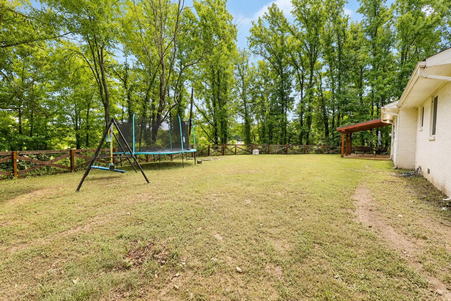 10093 Mt Carmel Road Brighton, TN 38011 - Photo 8 of 36 Expansive backyard featuring a white brick exterior, a covered patio with wooden beams, and a wooden fence