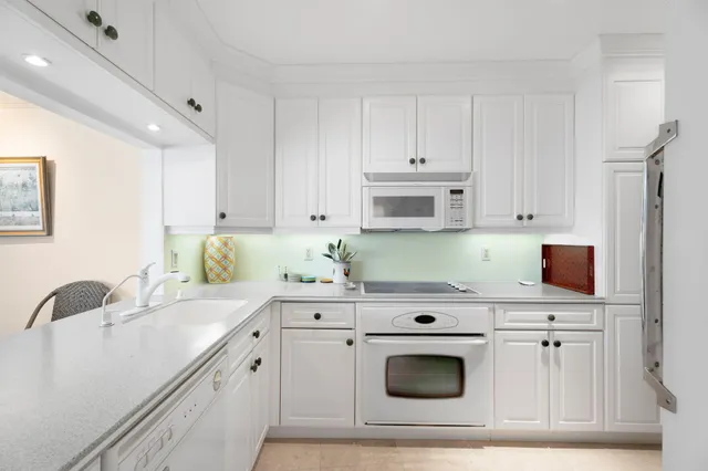 a kitchen with granite countertop white cabinets and white appliances