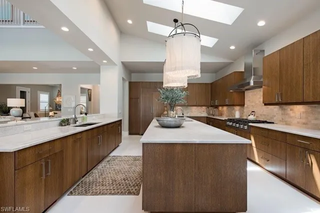 a large kitchen with stainless steel appliances a large counter top a sink a stove and a refrigerator