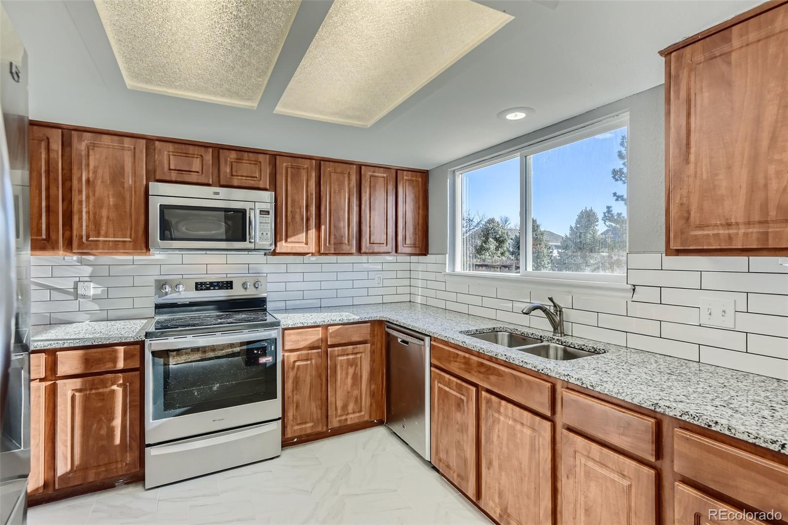 642 Northridge Road Highlands Ranch, CO 80126 - Photo 2 of 31 a kitchen with stainless steel appliances granite countertop a sink stove and microwave