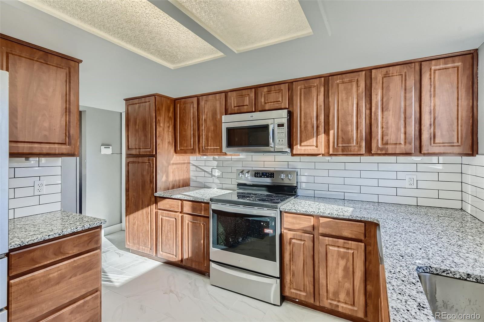 642 Northridge Road Highlands Ranch, CO 80126 - Photo 3 of 31 a kitchen with stainless steel appliances granite countertop a stove microwave and refrigerator