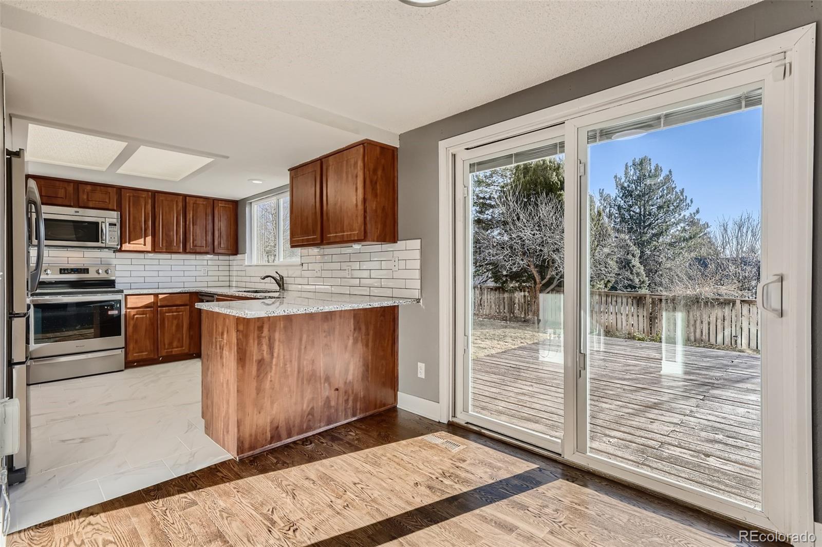 642 Northridge Road Highlands Ranch, CO 80126 - Photo 6 of 31 a kitchen with granite countertop wooden cabinets stainless steel appliances and a counter top space